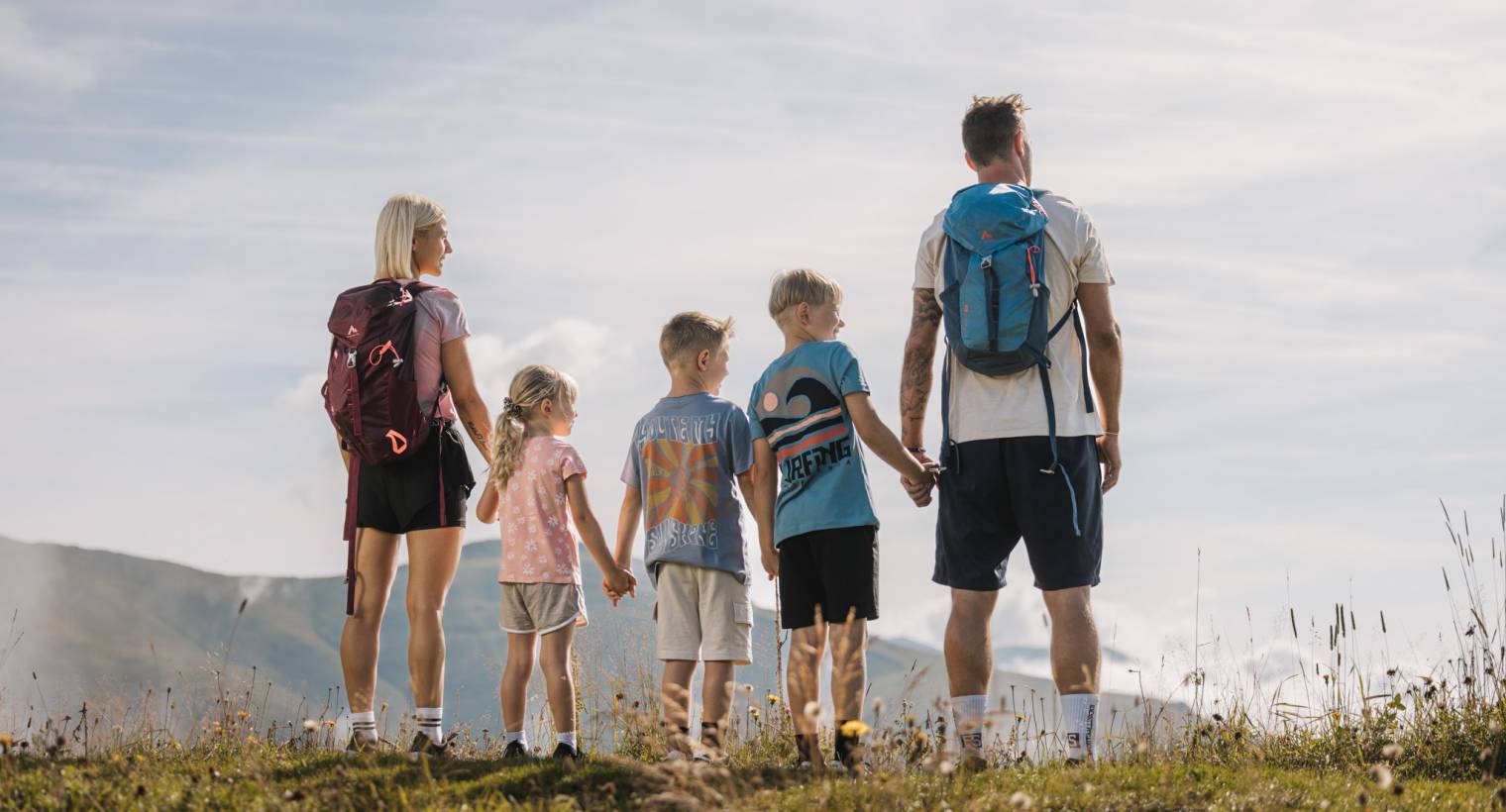 Familie steht Hand in Hand auf einem Berg in Tirol