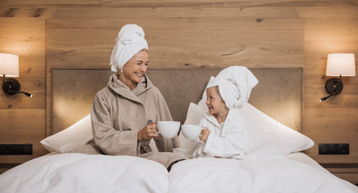 Tochter und Mutter trinken einen Tee im Bett
