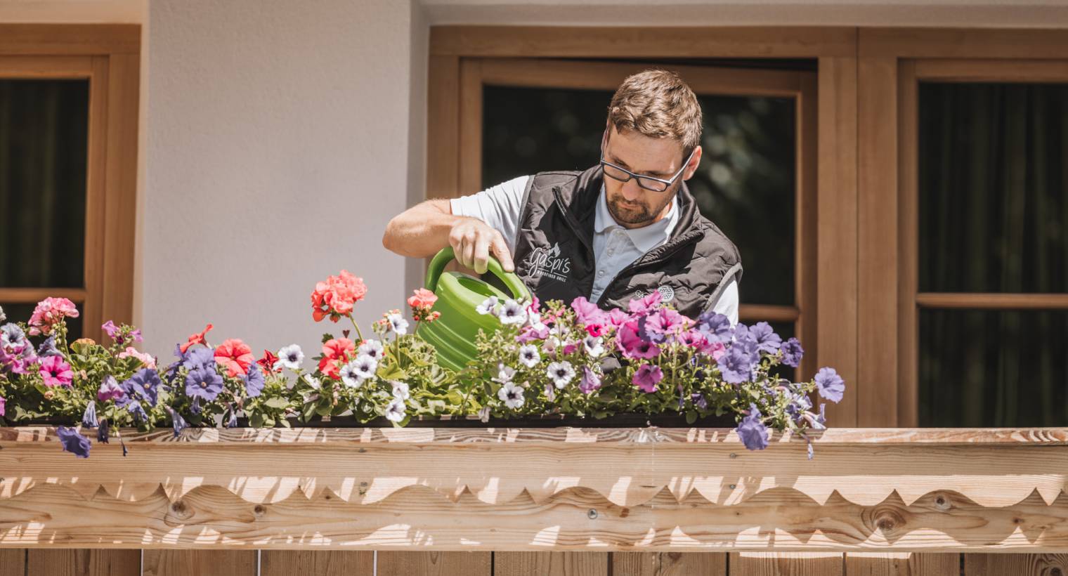 Mitarbeiter vom Hotel gießt die Blumen auf dem Balkon