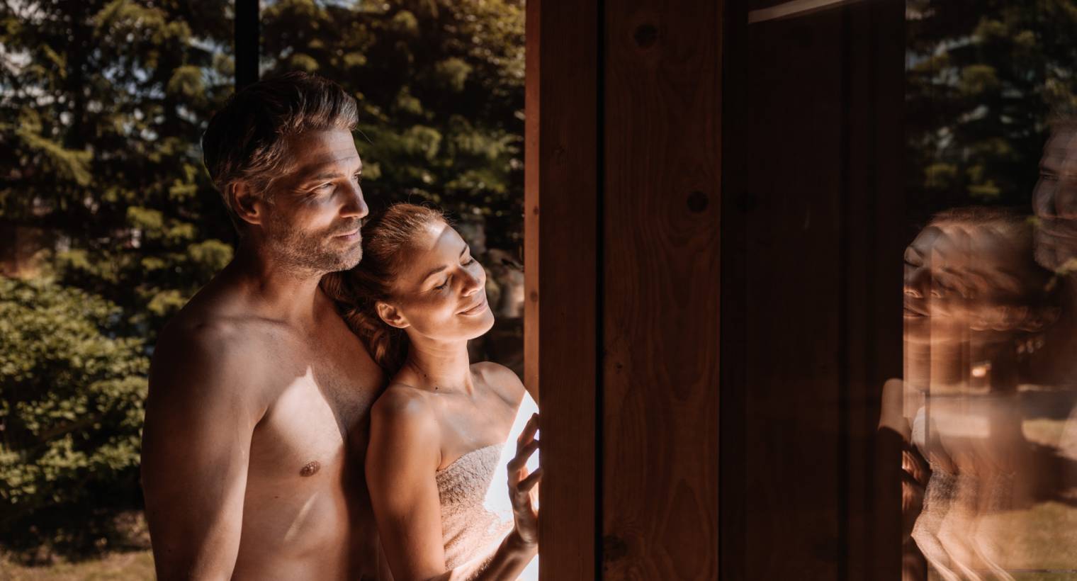 Paar stehen am Panoramafenster der Sauna