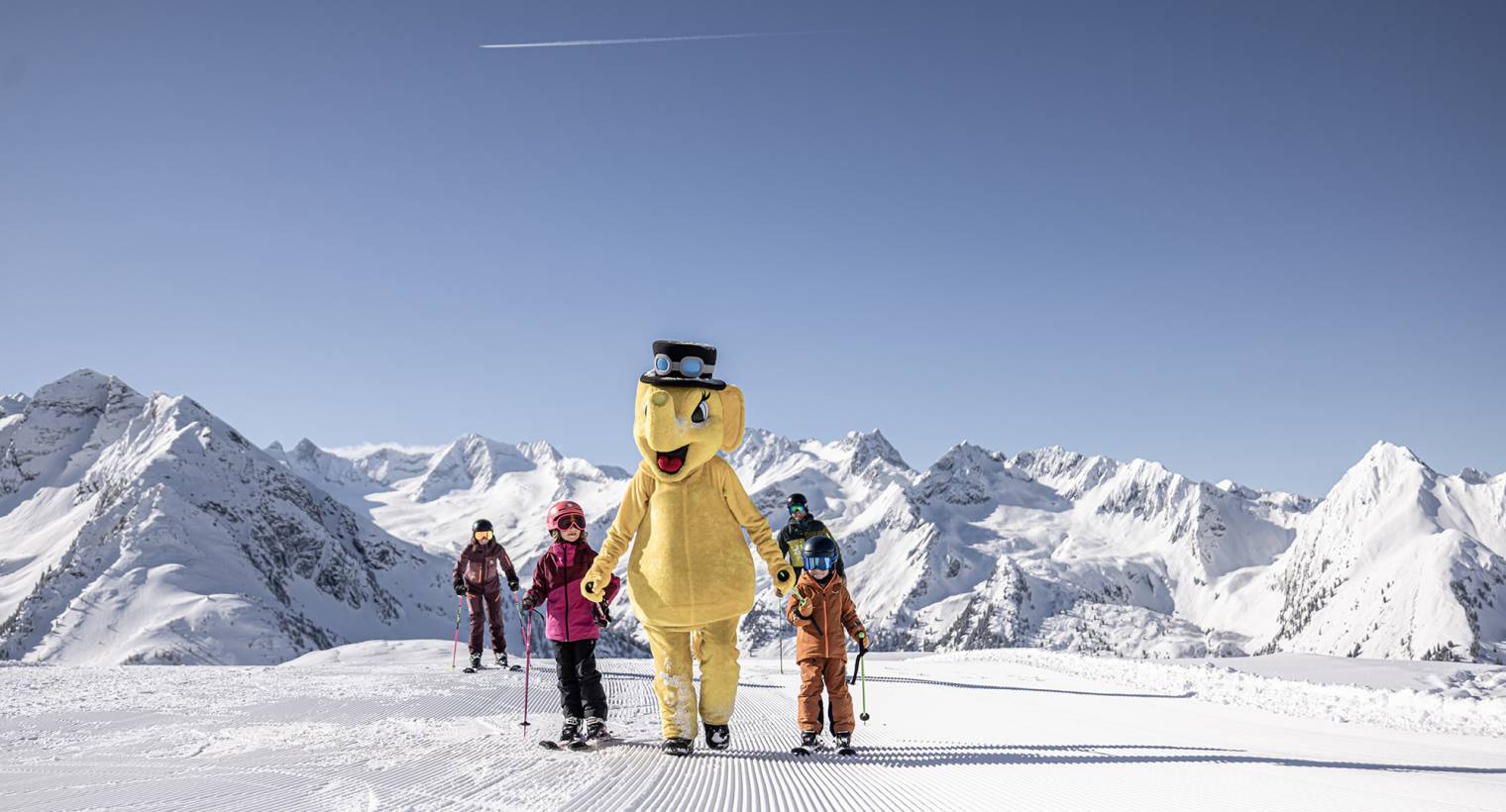 Kinder mit Maskottchen Elefant beim Ski fahren im Zillertal