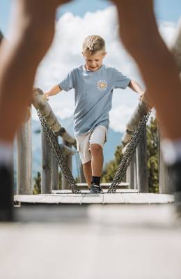 Kind läuft entlang einer kleinen Hängebrücke