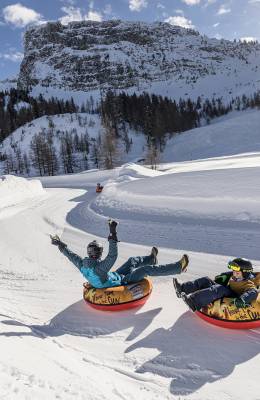 Zwei Personen haben spaß beim Snowtubing entlang einer Piste im Zillertal