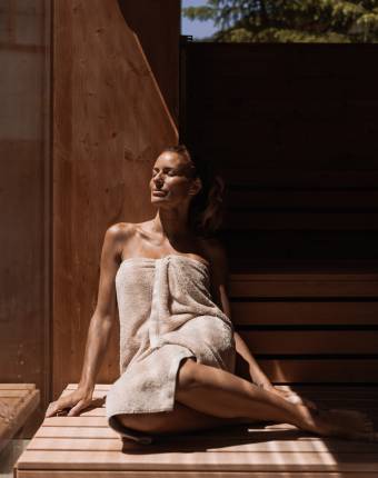 Frau genießt die Sonne auf der Haut in der Holzsauna