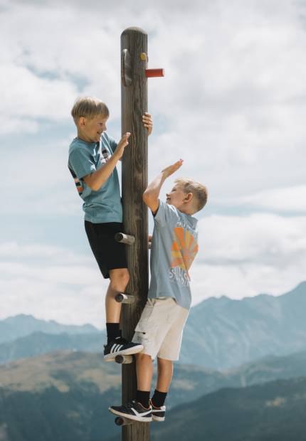Zwei Brüder klettern einen Pfosten hinauf