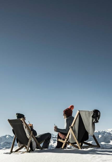 Personen entspannen in Liegestühlen auf dem Gipfel bei der Kristallhütte