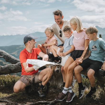 Wanderführer zeigt einer Familie den Weg auf einer Landkarte