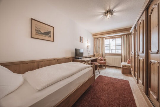 Gemütliches Schlafzimmer mit Holzdetails und Fernseher.