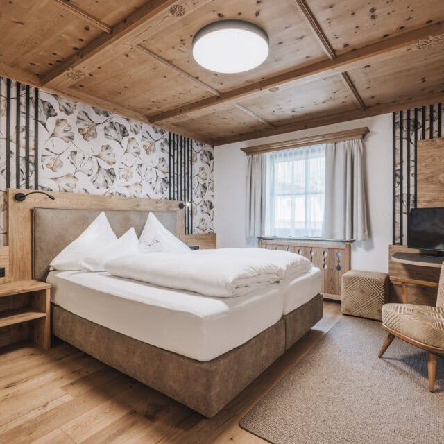 doppelzimmer auerberg2 Gemütliches Schlafzimmer mit Holzdekor und Pflanzenmotiv.