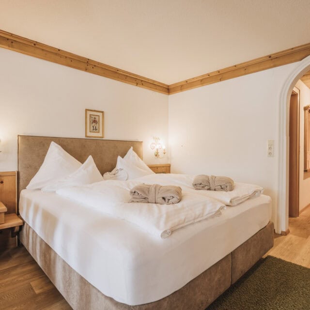 Gemütliches Doppelzimmer mit Holzdetails und Betten.