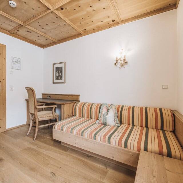 einzelzimmer de luxe3 Gemütlicher Wohnraum mit Holzdetails und Sofa