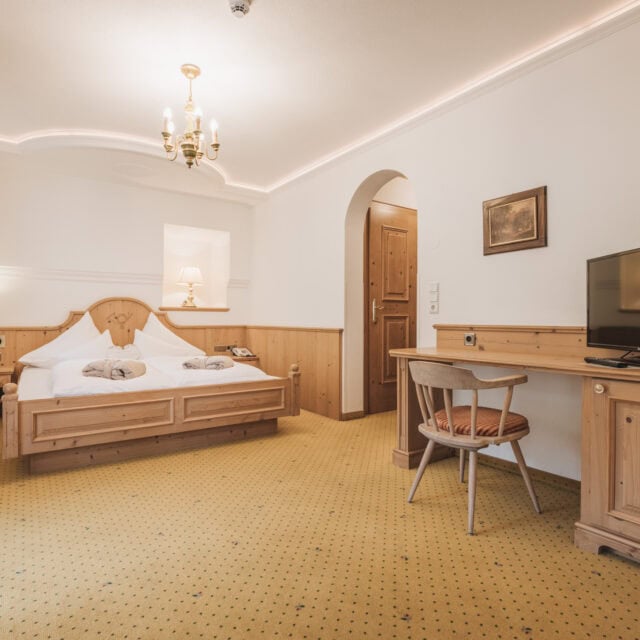 Gemütliches Hotelzimmer mit Holzdetails und TV.