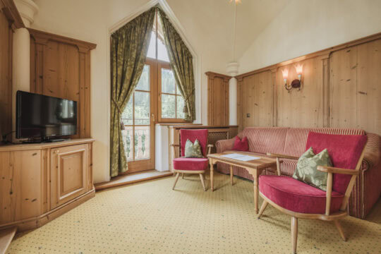 Gemütlicher Wohnbereich mit TV und Fenstern.