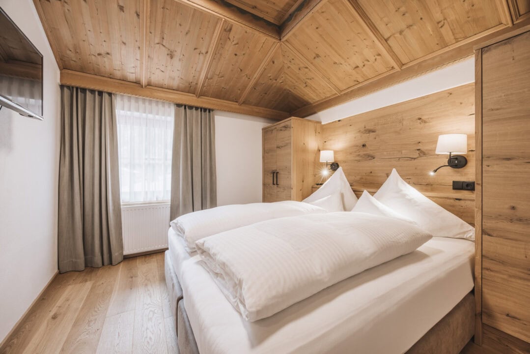 Gemütliches Zimmer mit Holzdecke und Doppelbett.