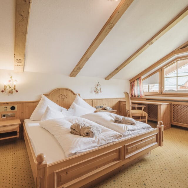 Gemütliches Schlafzimmer mit Fenstern und Holzmöbeln.