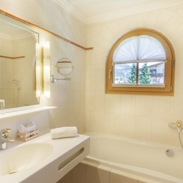 Helles Badezimmer mit Badewanne und Fenster.