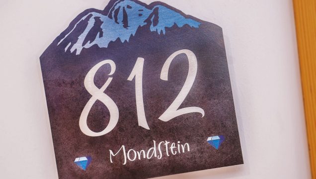 Hausnummer 812 mit Bergmotiv und Edelsteinen.