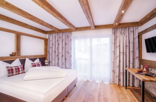 Helles Schlafzimmer mit Holzdetails und Vorhängen