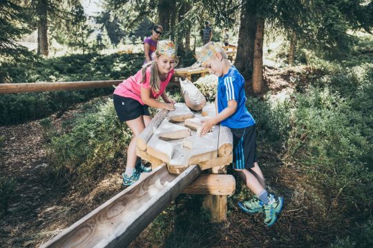 Kinder spielen im Wald mit Holzspielzeug.