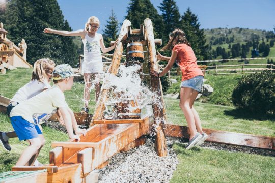Kinder spielen mit Wasser auf einem Spielplatz.