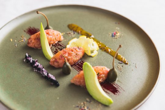 Gourmetgericht auf grünem Teller mit Garnitur.