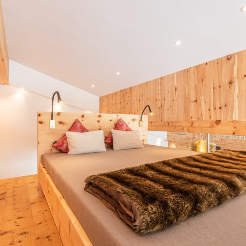 Gemütliches Schlafzimmer mit Holzdetails und Kissen.
