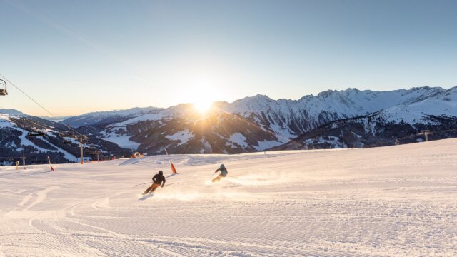 Skifahrer auf verschneiter Piste bei Sonnenuntergang