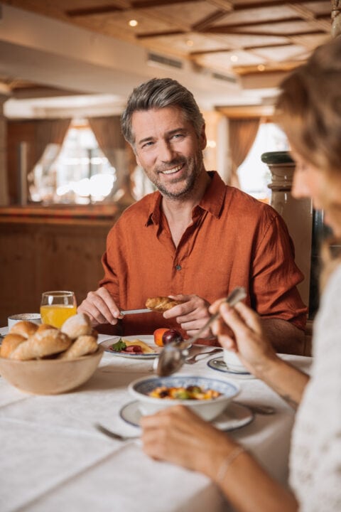 Mann genießt Frühstückstisch mit Freunden.