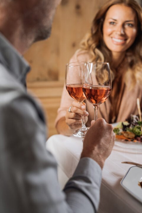 Zwei Personen stoßen mit Gläsern an.