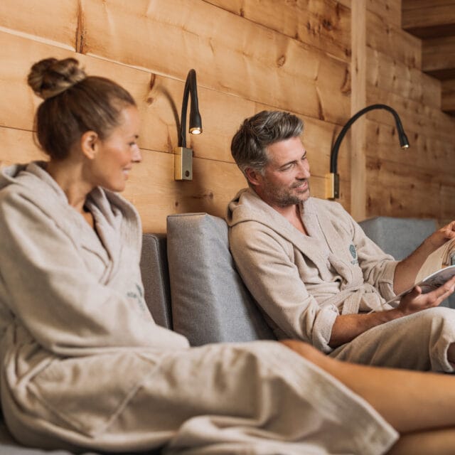 Entspanntes Paar im Wellnessbereich liest zusammen.