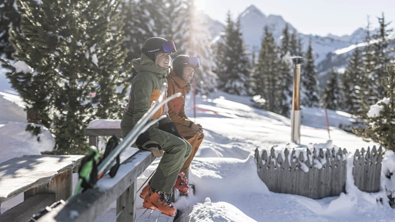 Zwei Skifahrer sitzen in der Winterlandschaft.