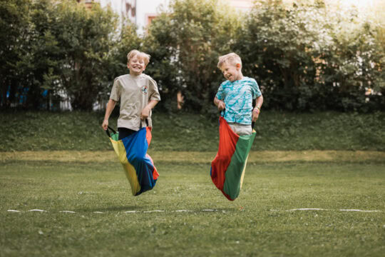 Zwei Kinder springen fröhlich in Säcken.