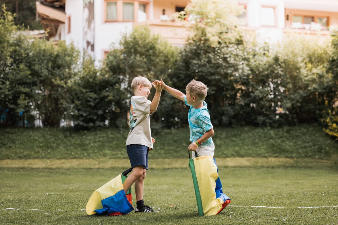 Zwei Kinder spielen im Freien mit Säcken.