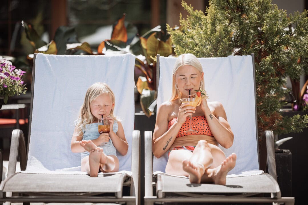 Mutter und Kind genießen Drinks am Pool.