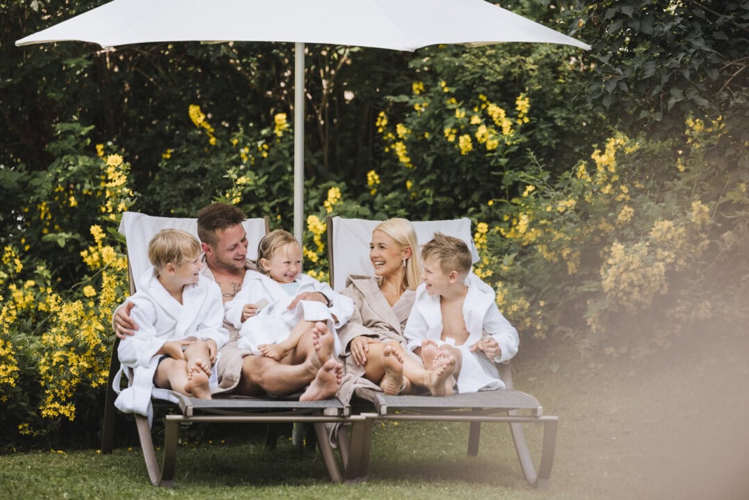 Familie entspannt im Garten mit Sonnenliege.