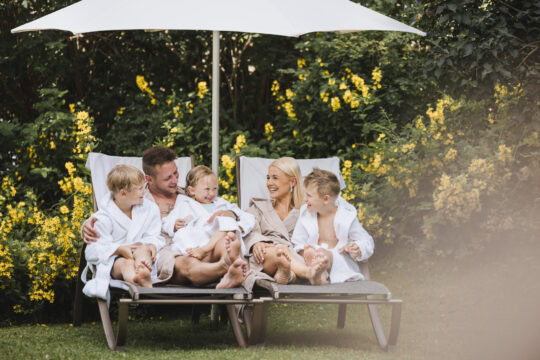 Familie entspannt im Garten mit Sonnenliege.