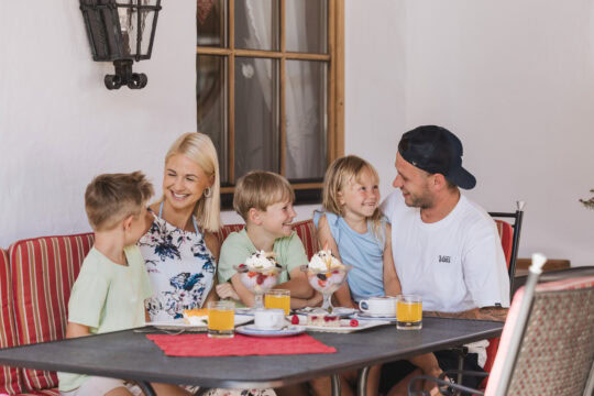 Familie genießt Eis und Getränke im Freien.