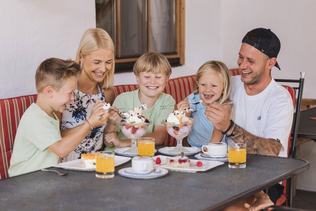 Familie genießt Eis und Getränke am Tisch.