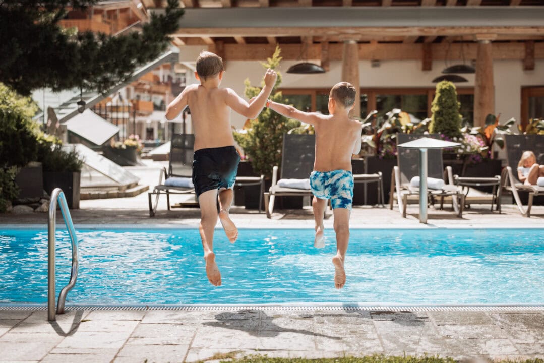 Zwei Jungen springen ins Schwimmbecken.