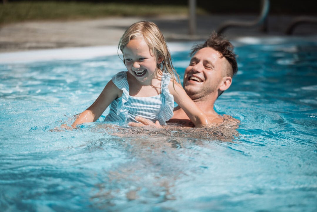 Lachendes Kind und Mann im Pool