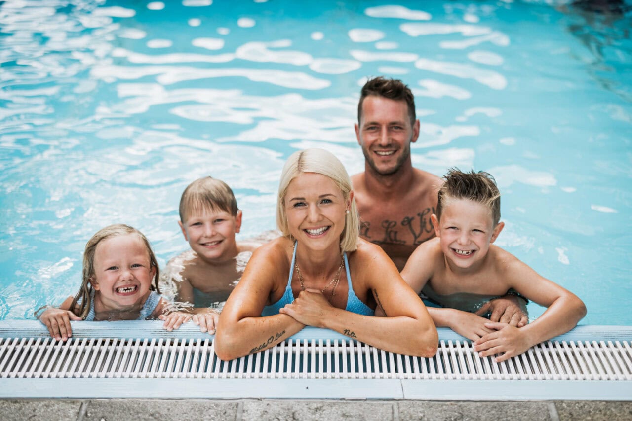 Familie spielt fröhlich im Pool.