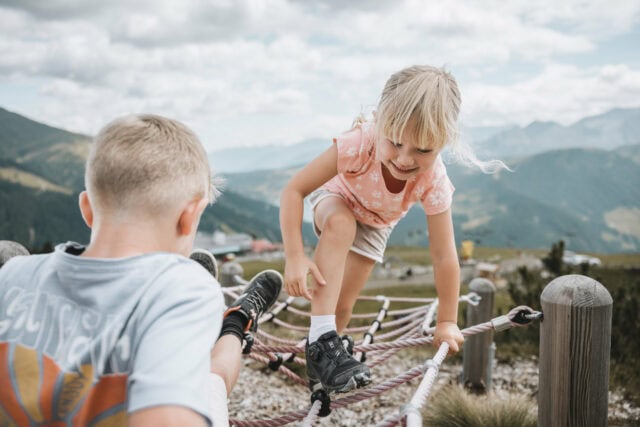 Kinder spielen auf einem Klettergerüst in den Bergen.