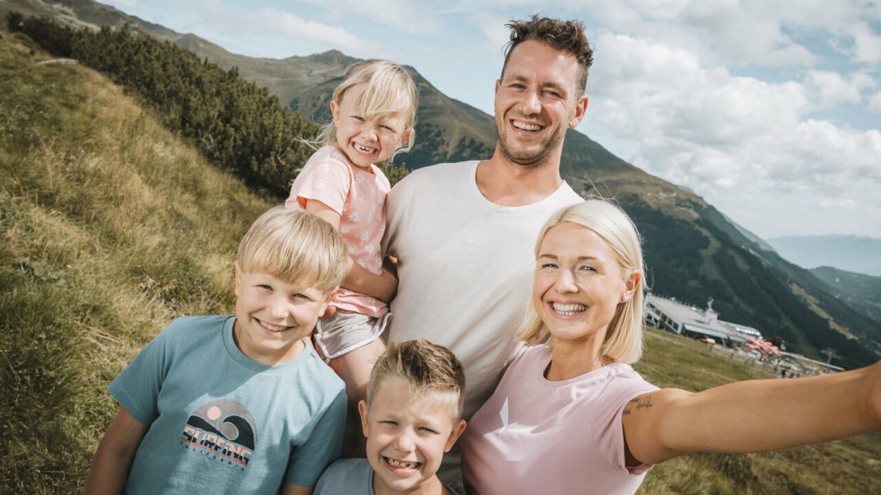 Familienporträt in den Bergen mit lächelnden Kindern.
