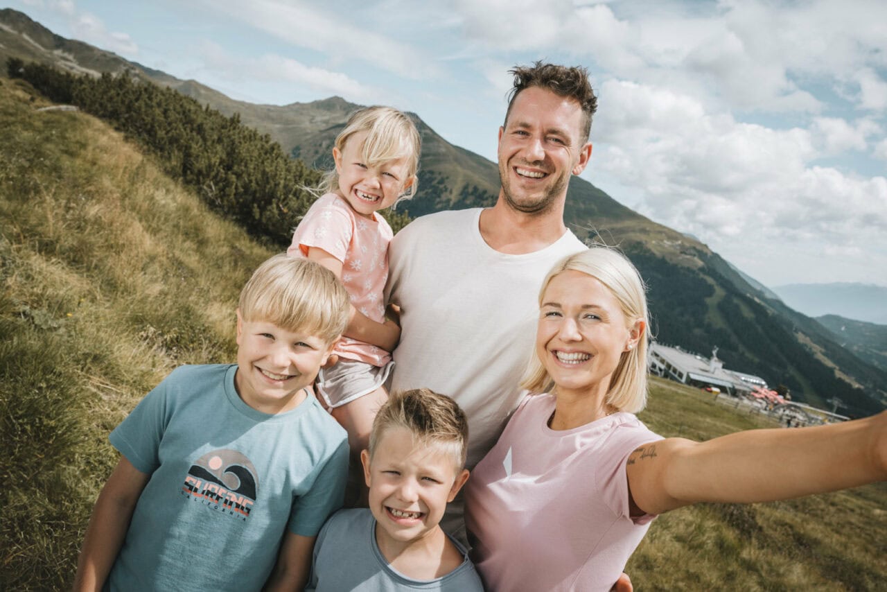 Familienporträt in den Bergen mit lächelnden Kindern.