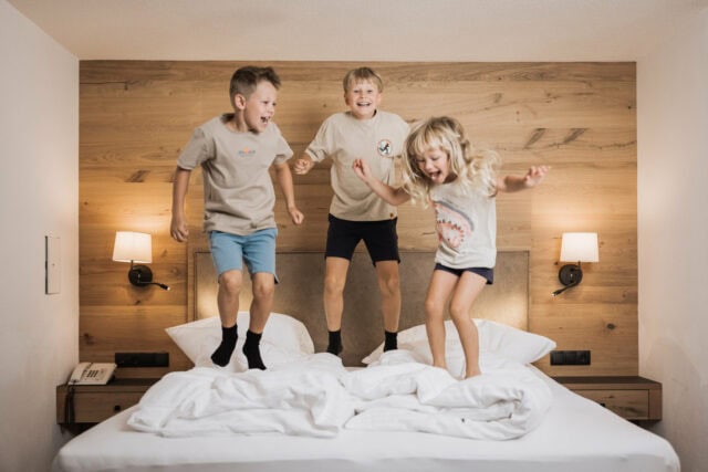 Kinder springen fröhlich auf einem Bett.